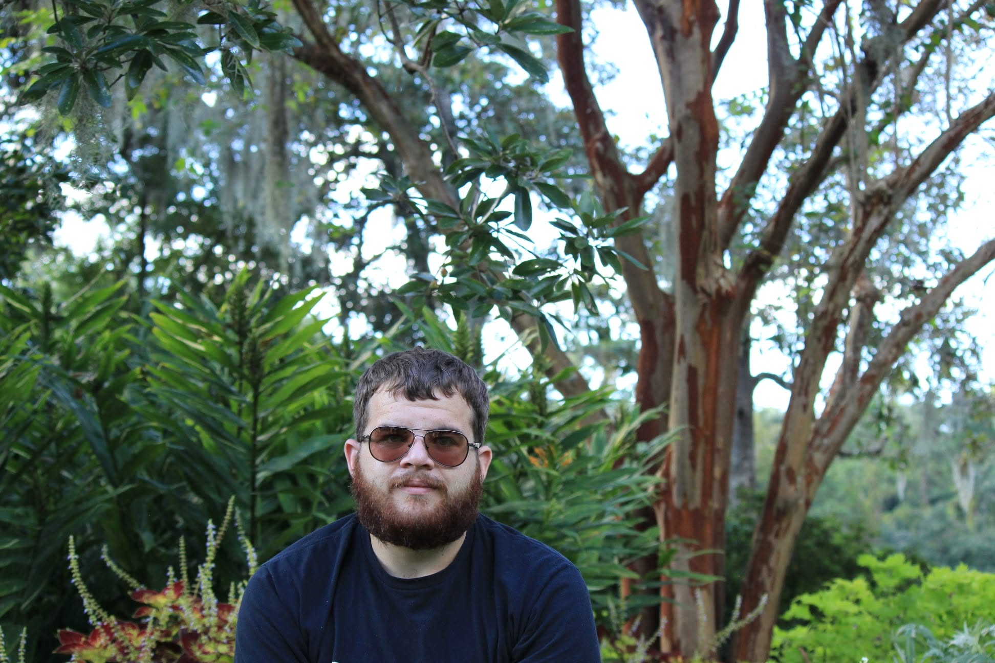 Portrait — man in sunglasses in a lush garden